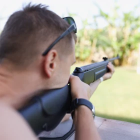 Man liegt auf einer Plattform und hat ein Lasergewehr in der Hand