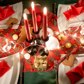weihnachtlich dekorierter Tisch mit roten Kerzen und weißen Tellern