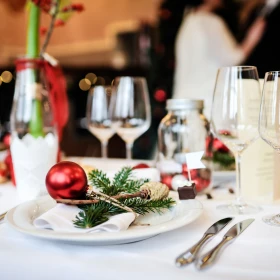 Platz an einem Tisch weihnachtlich dekoriert, weiße Serviette, Tannengrün und rote Weihnachtskugel