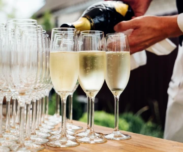 Person gießt Sekt in mehrere Gläser