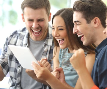 Personen schauen auf ein Tablet und freuen sich