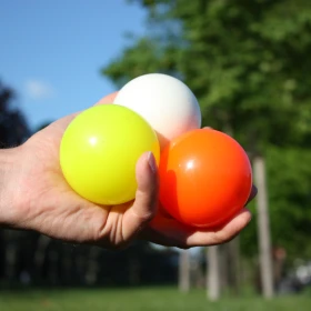 Bälle in gelb, weiß und orange in einer Hand