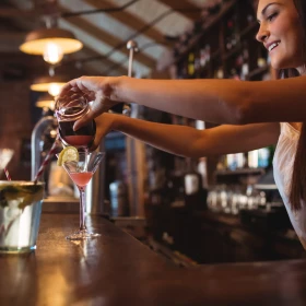 Cocktail wird von einer Barkeeperin eingegossen