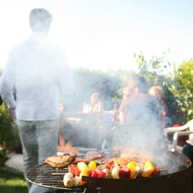 Grill im Vordergrund, im Hintergrund eine Personengruppe