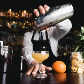 ein gelber Cocktail wird in ein Glas gefüllt