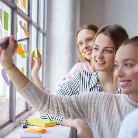 Gruppe beschreibt Post-its und klebt diese an Fenster