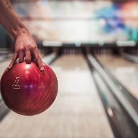 rote Bowlingkugel in den Grifflöchern festgehalten