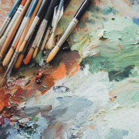 verschiedene Pinsel auf einer bemalten Leinwand