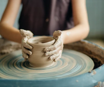 Frau formt eine Tasse aus Ton