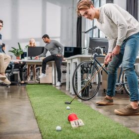 Mann spielt Golfball in roten Becher