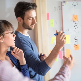 Meeting, Mann schreibt etwas auf einen Klebezettel an eine Wand