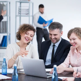 Personen sitzen vorm Laptopn und beraten sich