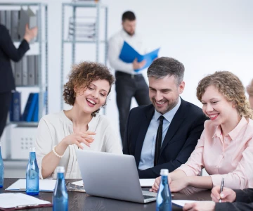 Personen sitzen vorm Laptopn und beraten sich