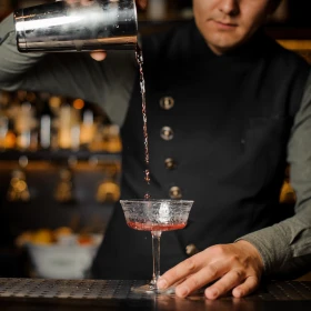 Cocktail wird vom Shaker in eine Glas geschüttet