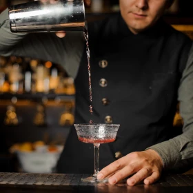 Cocktail wird vom Shaker in eine Glas geschüttet