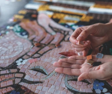 Person legt einzelne Mosaiksteine in das Gesamtbild