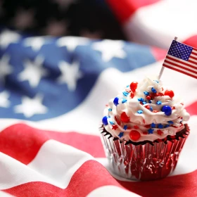 Cupcake mit amerikanischer Flagge und Dekoration aus Streuseln in rot, blau steht auf einer amerikanischen Flagge