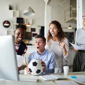 Business Menschen schauen Fußball auf einem Computer am Schreibtisch, Fußball auf dem Tisch, Menschen freuen sich und jubeln