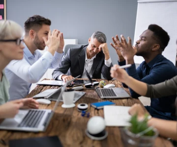 5 Personen bei einem Meeting diskutieren, angespannte Stimmung