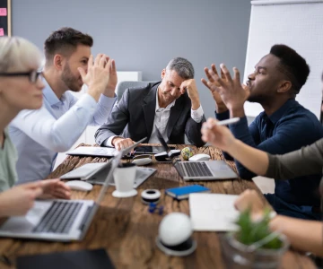 5 Personen bei einem Meeting diskutieren, angespannte Stimmung