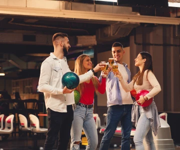 EVINTA_Bowling-Weihnachtsfeier_Bild01 Gruppe hält Bowlingkugel und stößt mit Bier an