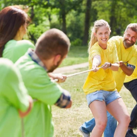 Team grün und gelb ziehen an einem Tau beim Tauziehen