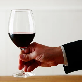 Hand hält elegant ein Rotweinglas