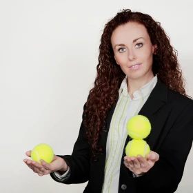 Frau jongliert mit 3 gelben Bällen