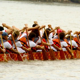 Gruppe paddelt gemeinsam in einem Drachenboot zum Ziel