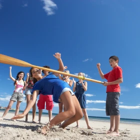 Gruppe beim Limbo tanzen am Strand