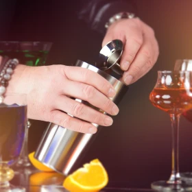 Shaker wird befüllt, Barkeeper mixt ein Getränk in einer Cocktail Bar