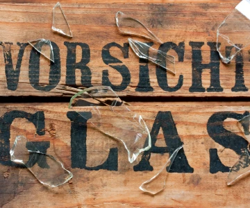 Holz mit Aufschrift "Vorsicht Glas", Glasscherben auf dem Holz