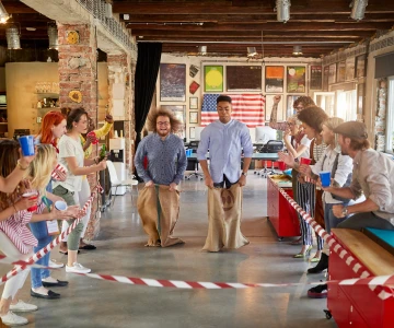 Menschen feuern 2 Teilnehmer beim Sackhüpfen an