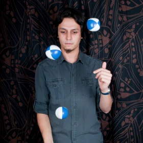 Mann jongliert mit weiß-blauen Bällen