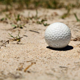 weißer Golfball im Sand