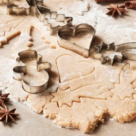 Plätzchen werden aus einem ausgerollten Teig ausgestochen, Schneemann, Herz, Sternschnuppe