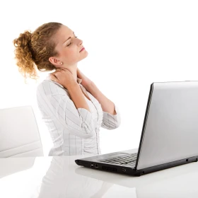 Frau massiert sich den Nacken aufgrund ihrer Sitzhaltung