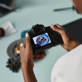 Nahaufnahme eines nicht erkennbaren Food-Fotografen, der eine Kamera mit einem Bild auf dem Bildschirm hält