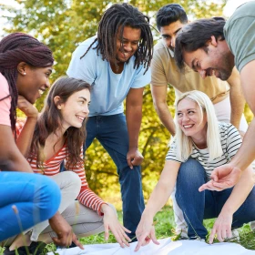 Gruppe von Freunden spielt Geländespiel mit Karte in der Natur