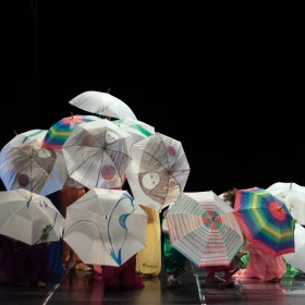 Gruppe mit Regenschirmen auf der Bühne