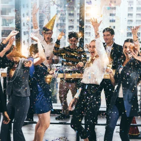 Businessmenschen feiern in einem Büro mit Sekt und Konfetti