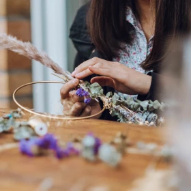 Frau bindest Blumenkranz mit lilanen Trockenblumen