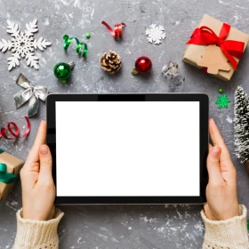 Tablet mit weihnachtlicher Dekoration im Hintergrund