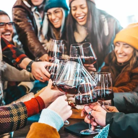 Gruppe mit Strickmützen beim Rotweintrinken
