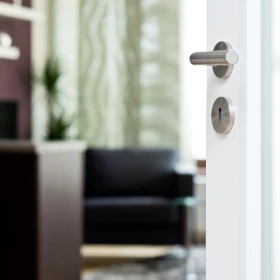 weiße Tür mit silbernem Schloß und Griff steht offen