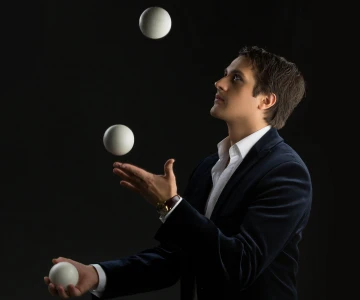 Mann jongliert mit weißen Bällen
