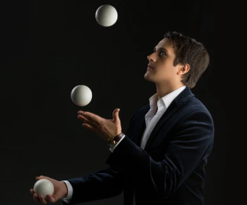 Mann jongliert mit weißen Bällen