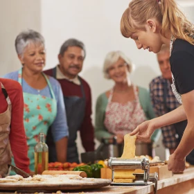 Frau zeigt einer Gruppe wie man Pasta zubereitet