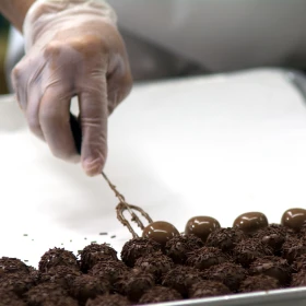 Pralinen werden mit Schokolade und Schokoladenstreusel verziert