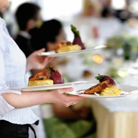 Kellnerin trägt drei Teller mit Essen